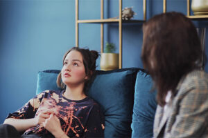 Girl leans back on couch and talks to therapist during bipolar disorder treatment 