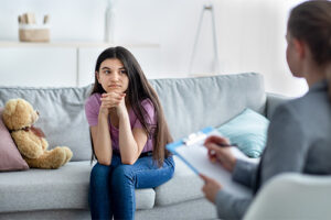 Teen sits on couch and talks to therapist during partial hospitalization program