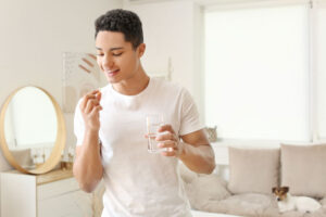 Teen gears up to take a pill with a glass of water during medication-assisted treatment