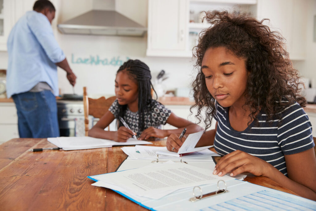 teen girl doing schoolwork at the kitchen table, practicing healthy routines and habits for self-care