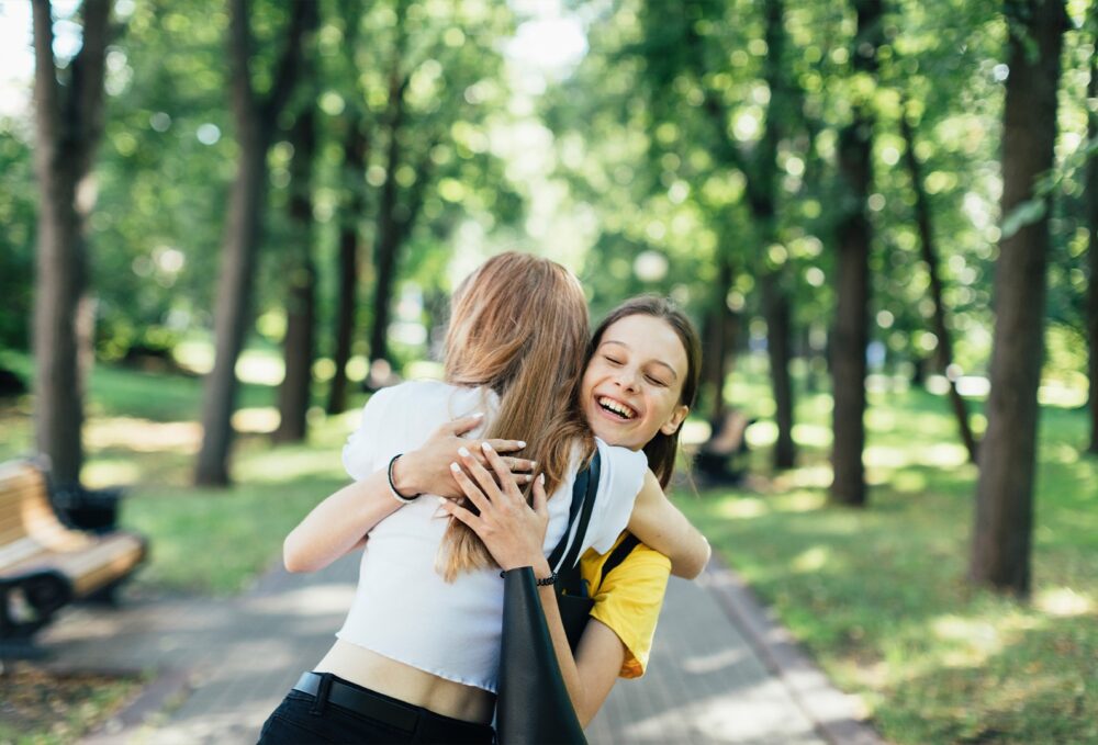 Teen girl hugging teen girl friend after she leaves adolescent treatment near Cleveland, Ohio.